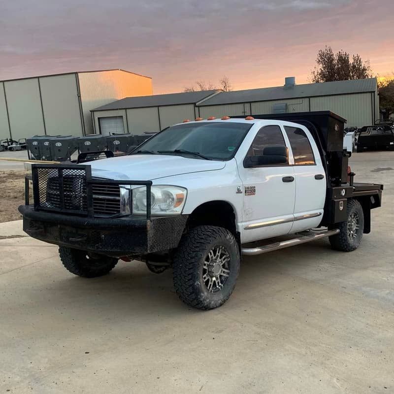 a white truck with a cake feeder attached to it is parked in a parking lot .