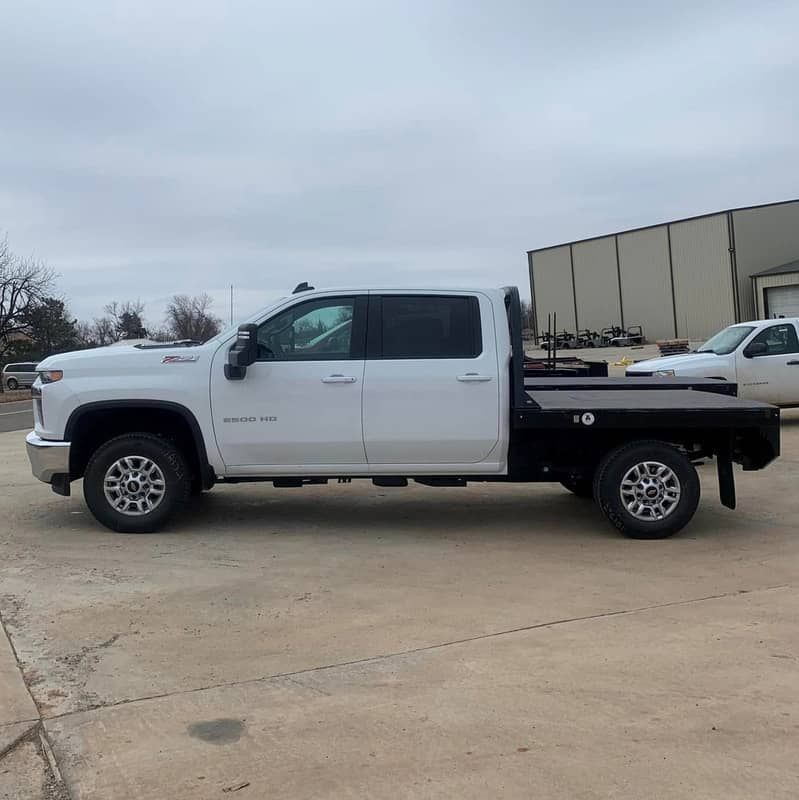 a white ram 4 door crew cab truck with a flat bed is parked in a parking lot .