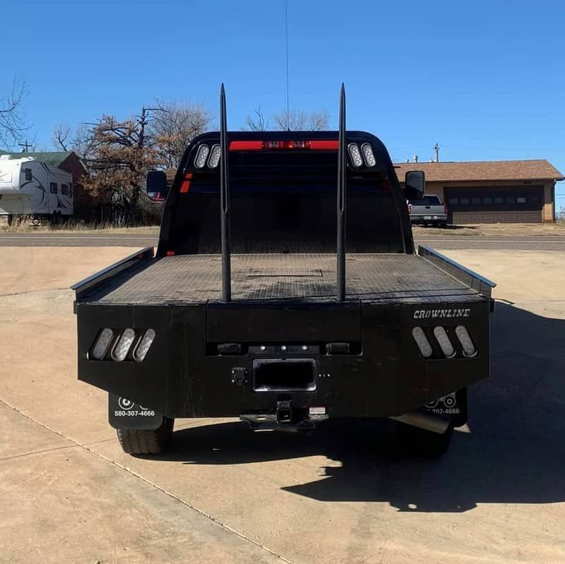 a black truck with a hay spike flat bed is parked in a parking lot