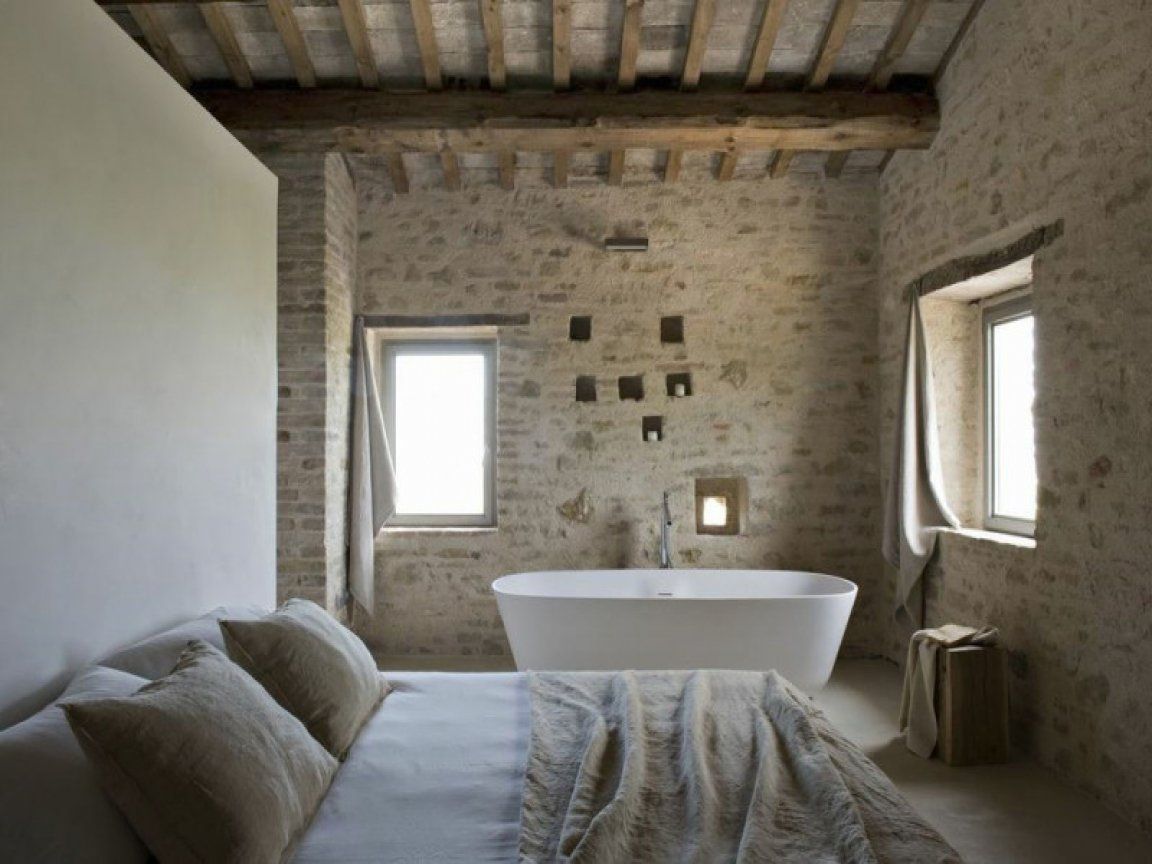 camera da letto con vasca e parete in pietra