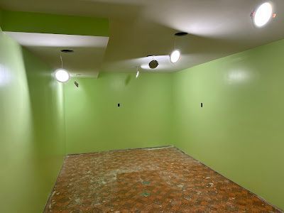 An empty room with green walls and a brown floor.