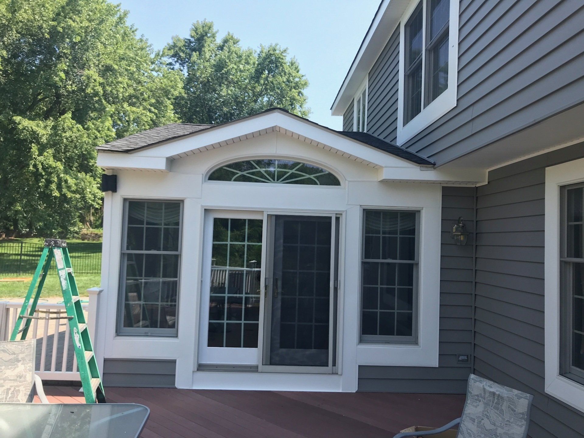 Back patio sunroom addition with white trim, gray siding, and glass double doors