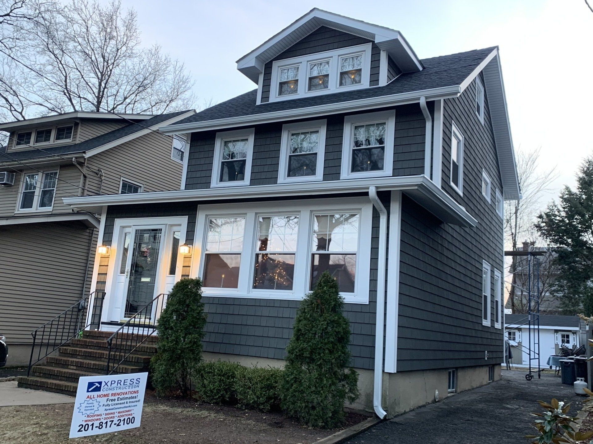 Gray two-story house with front porch, white trim, and a real estate sign in front
