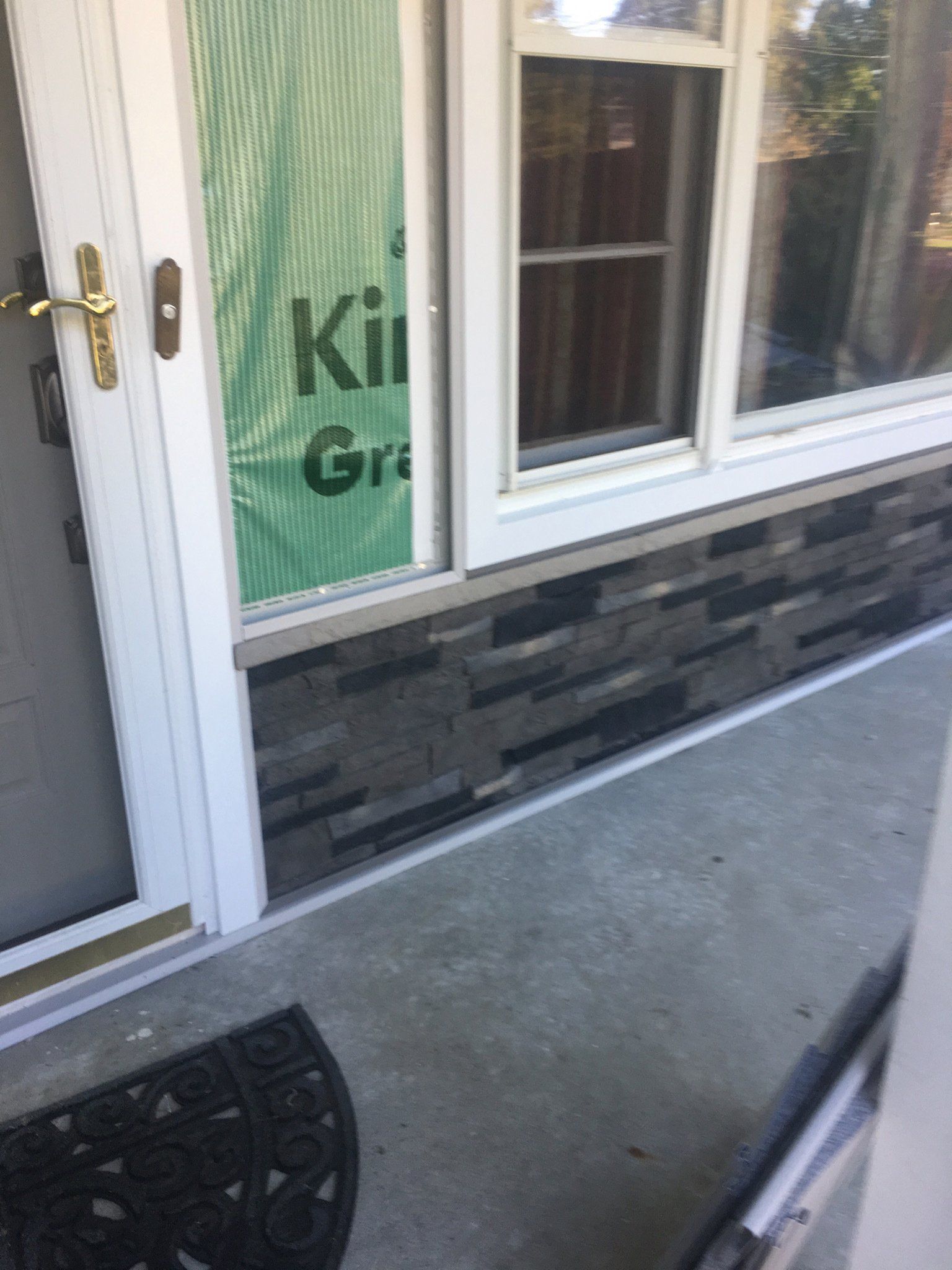 Front door and window of a storefront with stone veneer and a concrete walkway