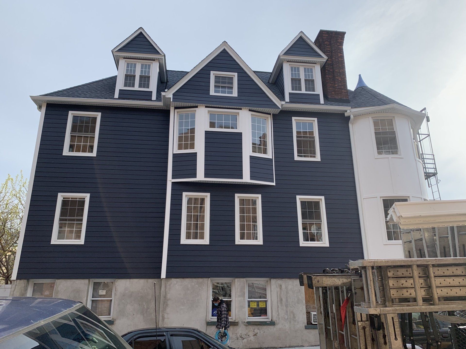 Three-story blue house with white trim and dormer windows under construction