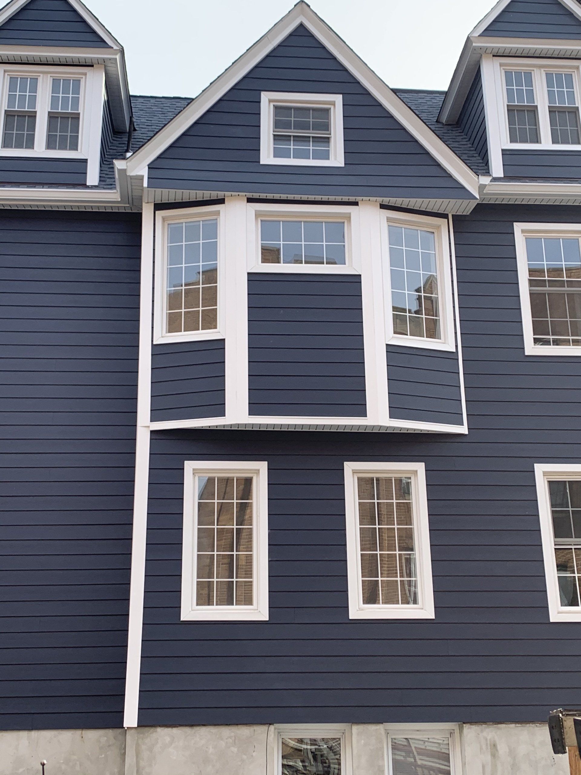Blue-gray house facade with white-trimmed windows and a small central bay window