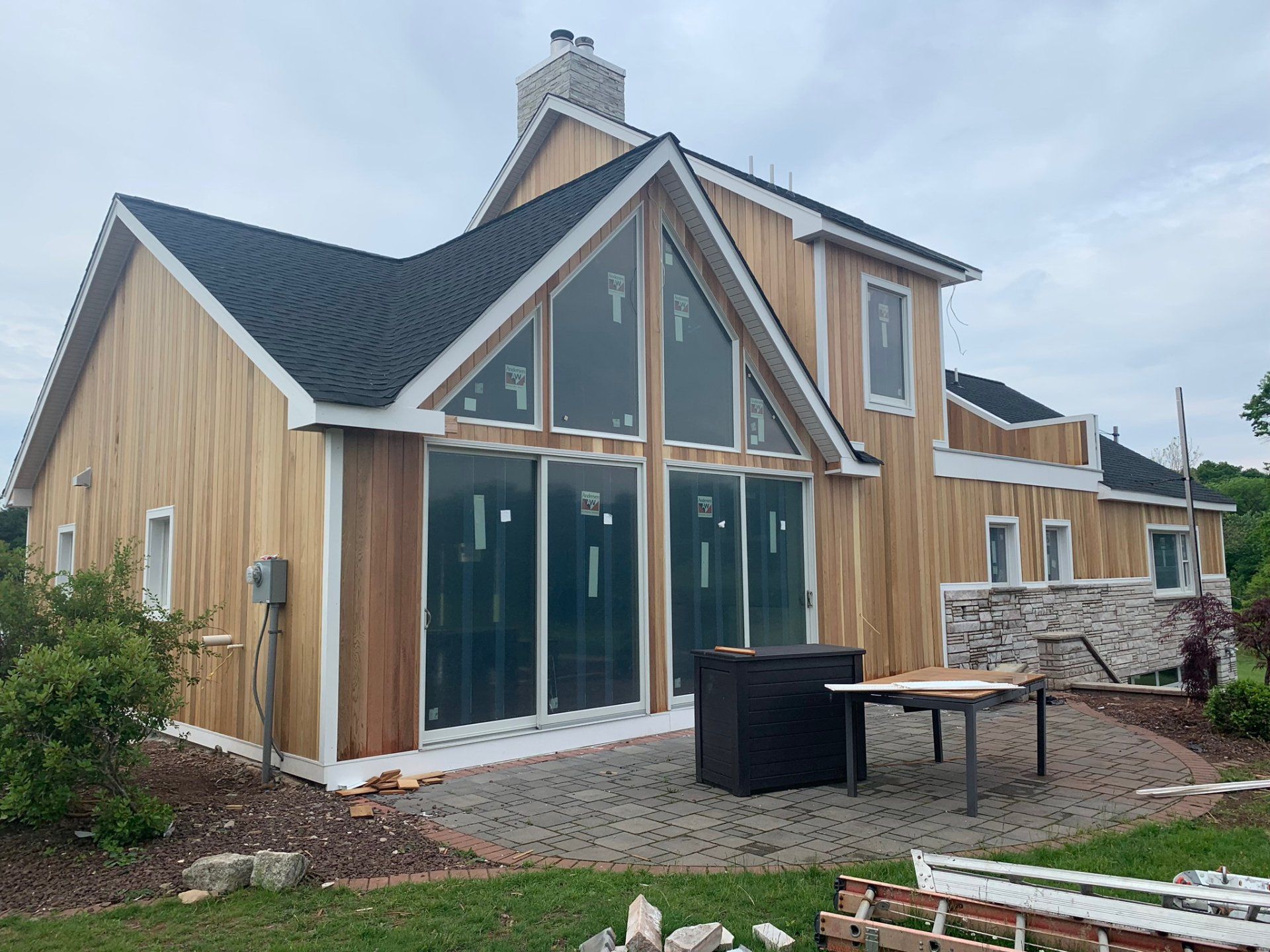 Modern wooden house with large glass front, steep roof, and landscaped yard