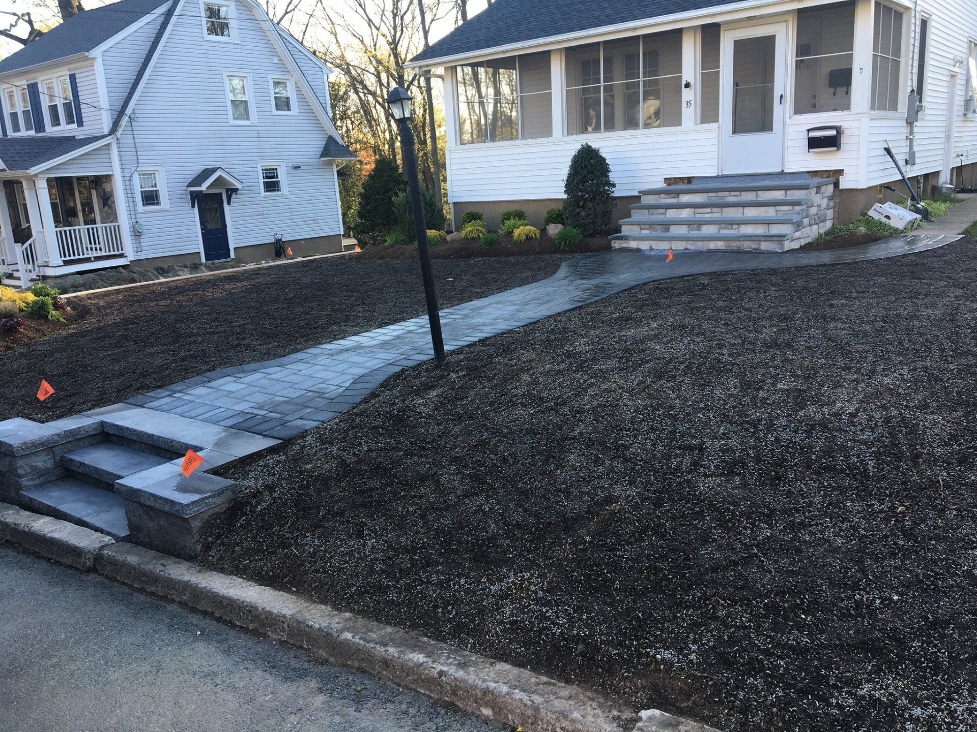 Freshly landscaped front yard with stone walkway and black mulch leading to a white house