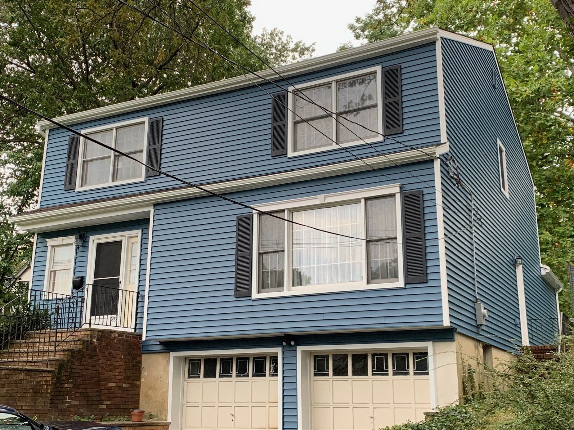 Blue two-story house with white trim and double garage doors, viewed from the street
