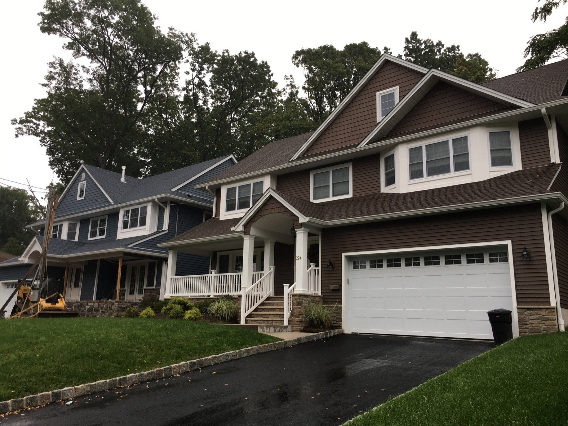 Row of suburban townhouses with dark siding, white trim, and wet driveways on a cloudy day