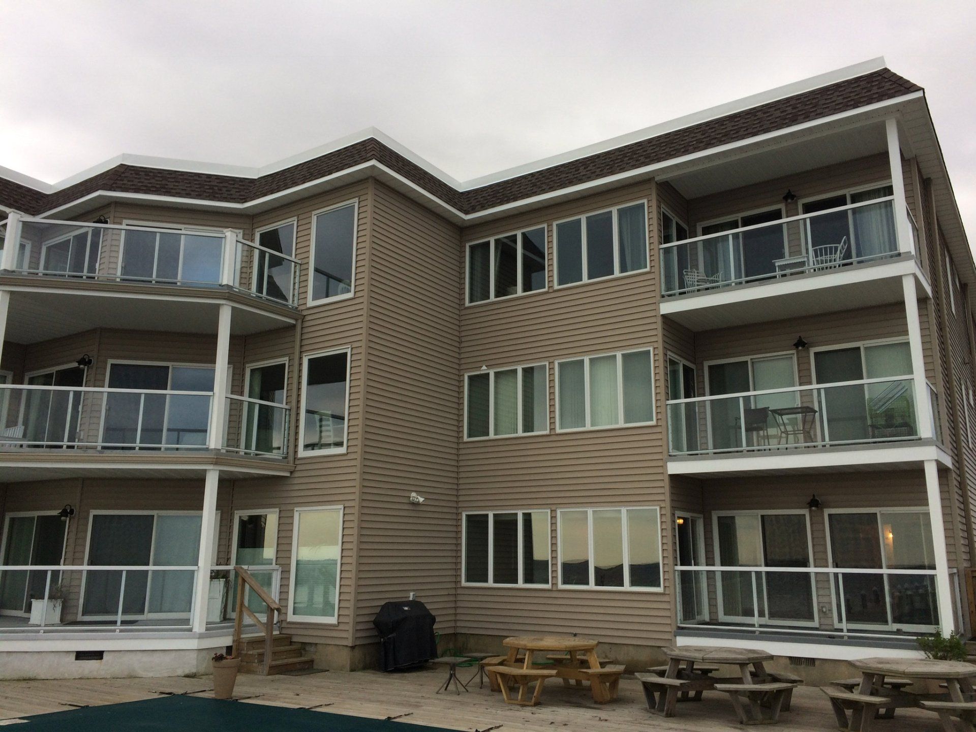 Three-story apartment building with balconies and large windows, viewed from a courtyard.
