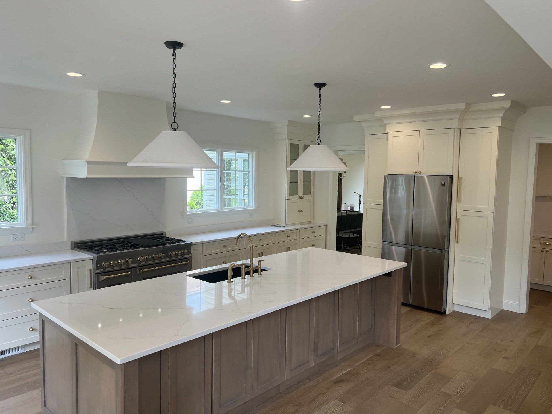 Bright modern kitchen with a large island, pendant lights, white cabinets, and stainless steel refrigerator