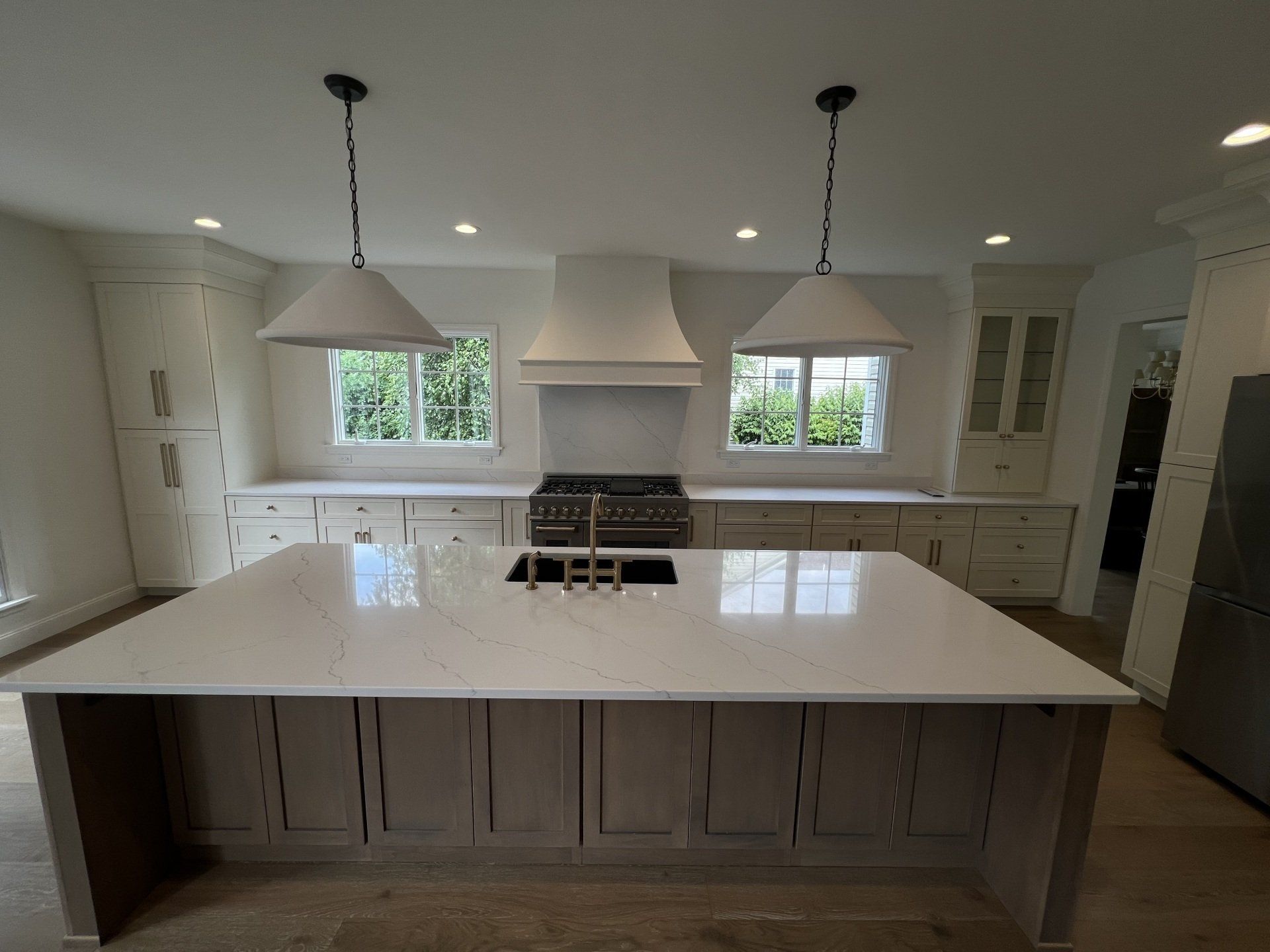 Bright modern kitchen with large island, white cabinets, pendant lights, and a gas range.
