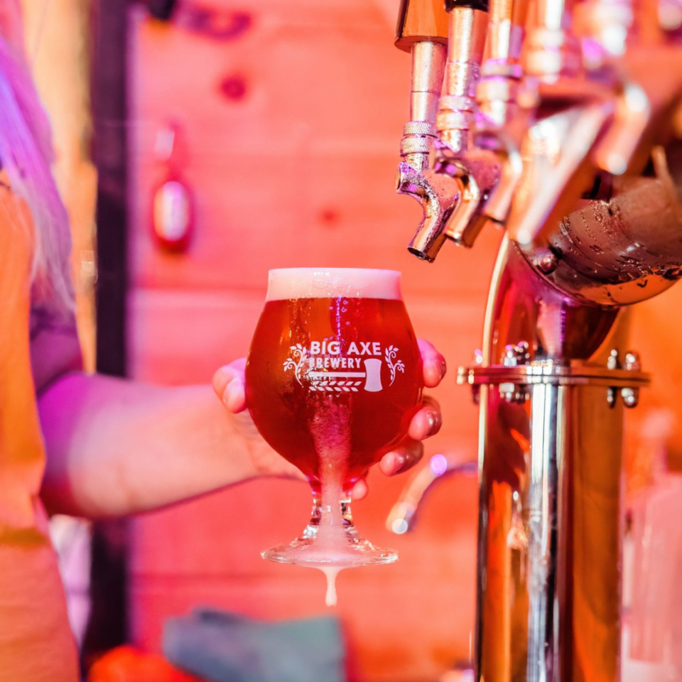 Person holding a glass of beer from a tap at Big Axe Brewery.