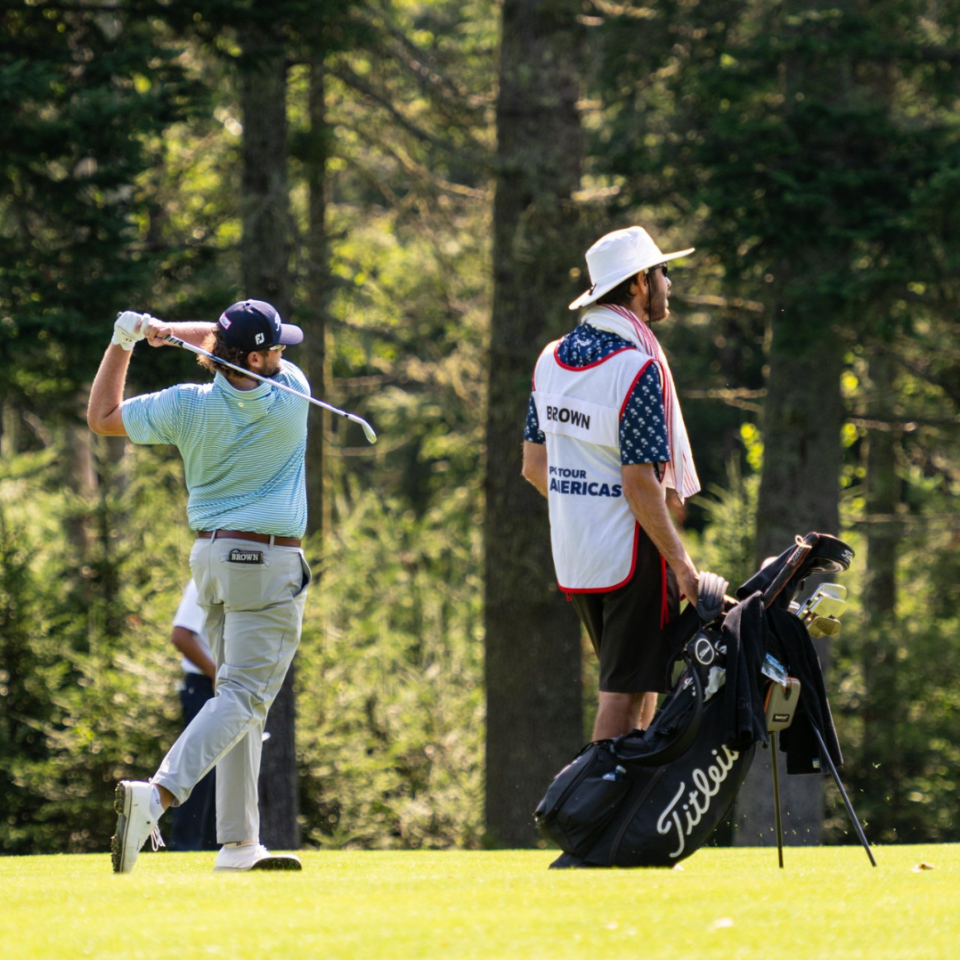 A woman is swinging a golf club on a golf course.