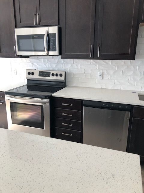 A kitchen with stainless steel appliances and brown cabinets