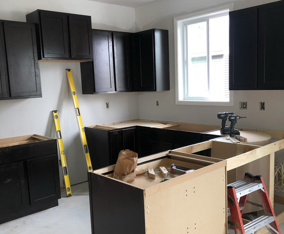 A kitchen under construction with black cabinets and a window.