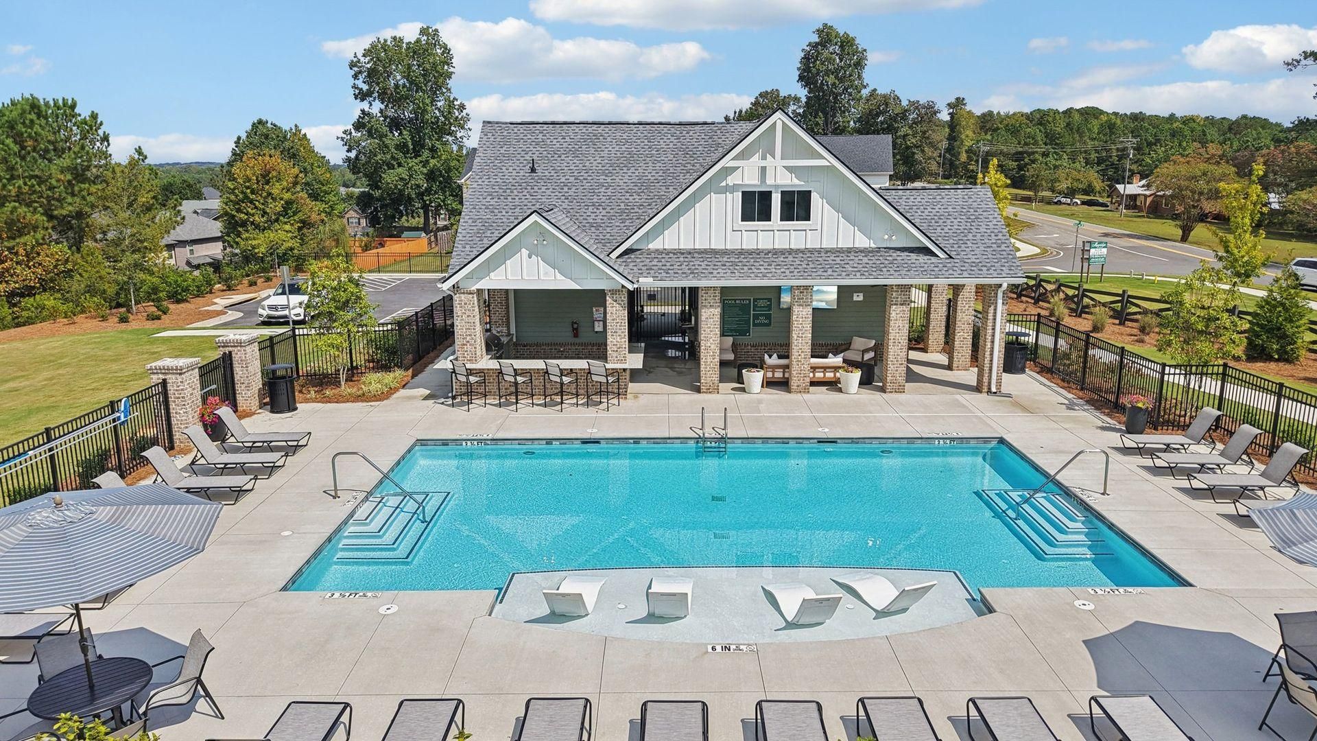 Luxury resort pool with lounge chairs and a clubhouse under a blue sky