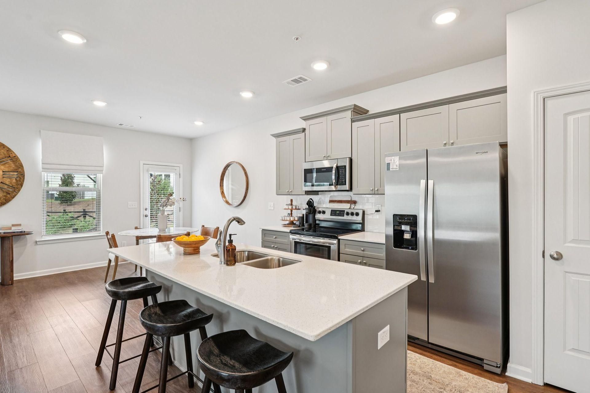 Bright modern kitchen with white cabinets, stainless steel fridge, and island with stools