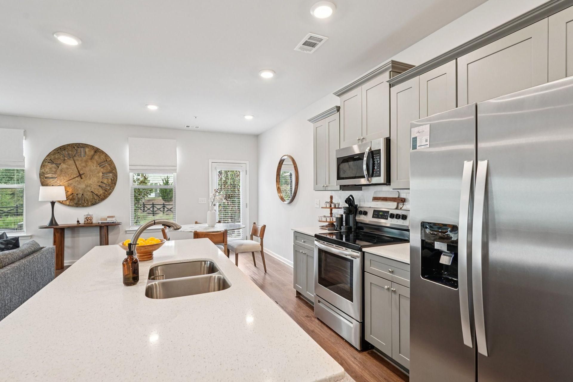 Bright modern kitchen with white island, stainless steel appliances, and open living area beyond