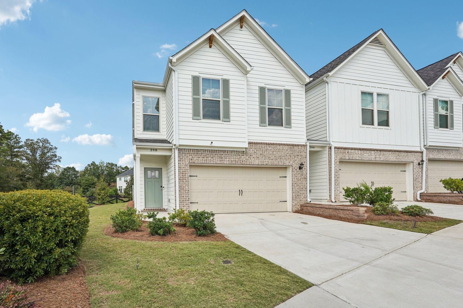 Two-story white suburban townhouse with garage, driveway, and small front lawn