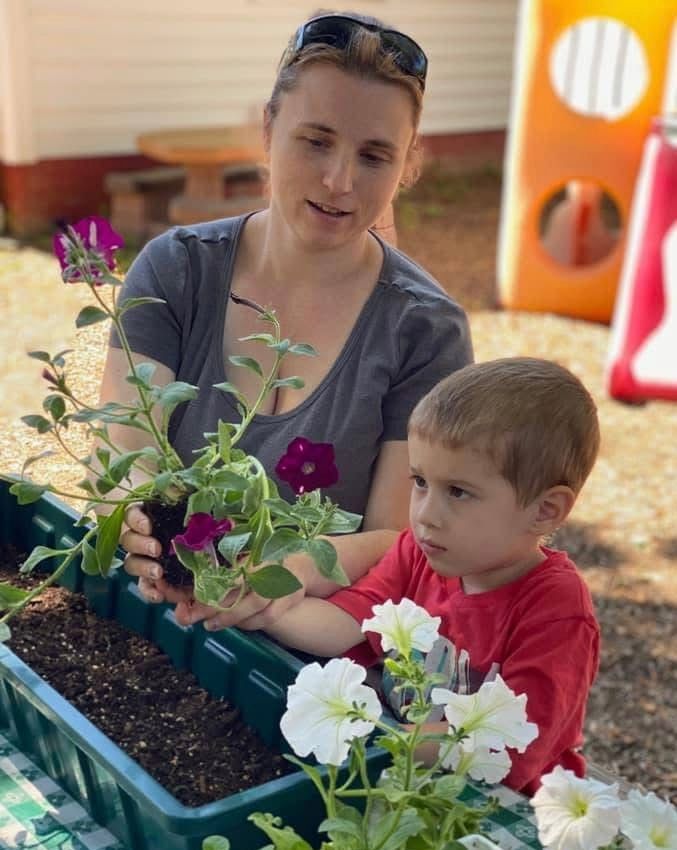 Adult and child gardening together with flowers in a planter
