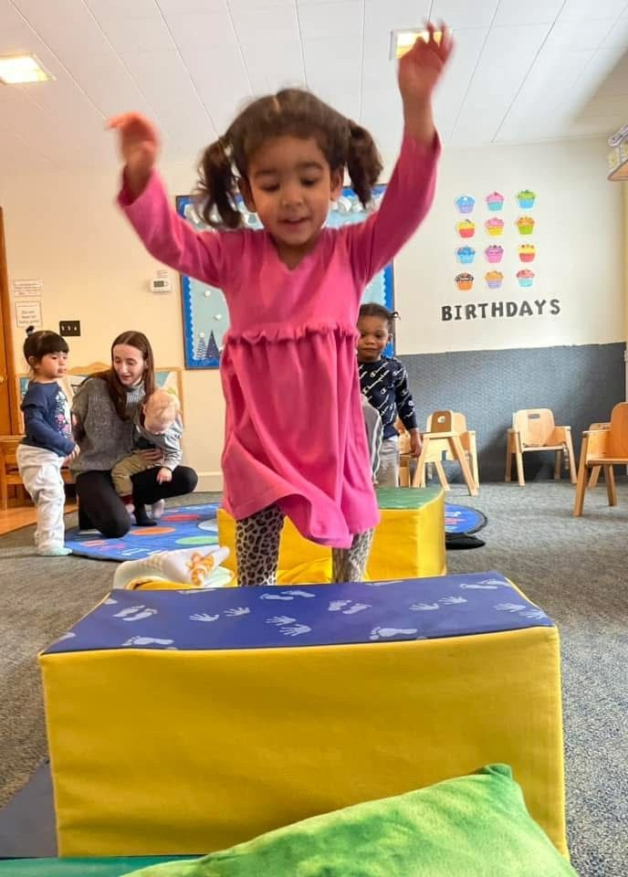 Child jumping onto a yellow-and-blue foam block at a birthday party room