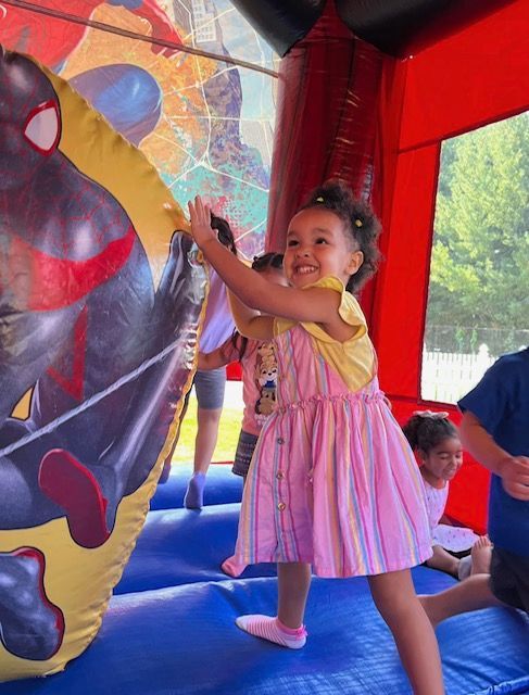Child smiling and climbing on a colorful inflatable play structure indoors