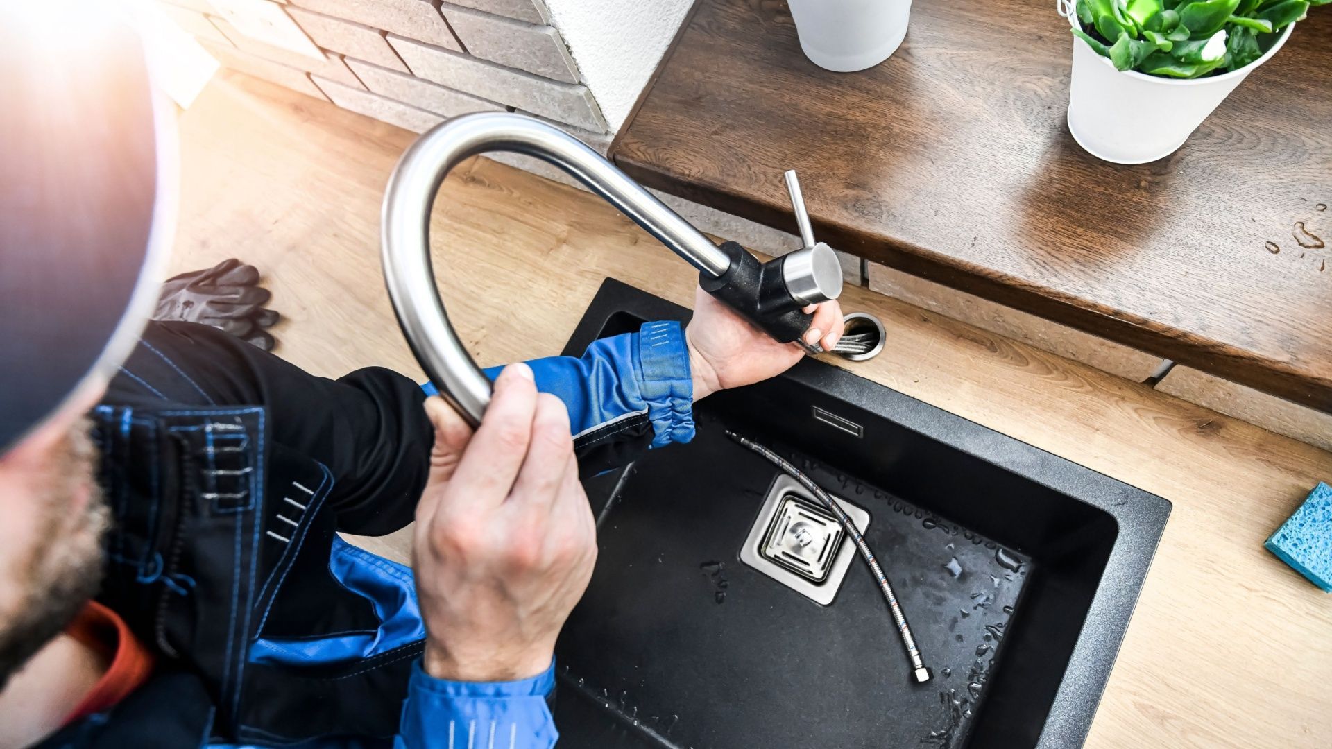 A man is fixing a faucet in a kitchen sink.