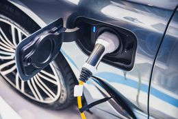 Electric car charging port with cable plugged into a silver vehicle’s side.