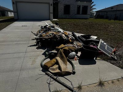 A pile of trash is sitting on the sidewalk in front of a house.