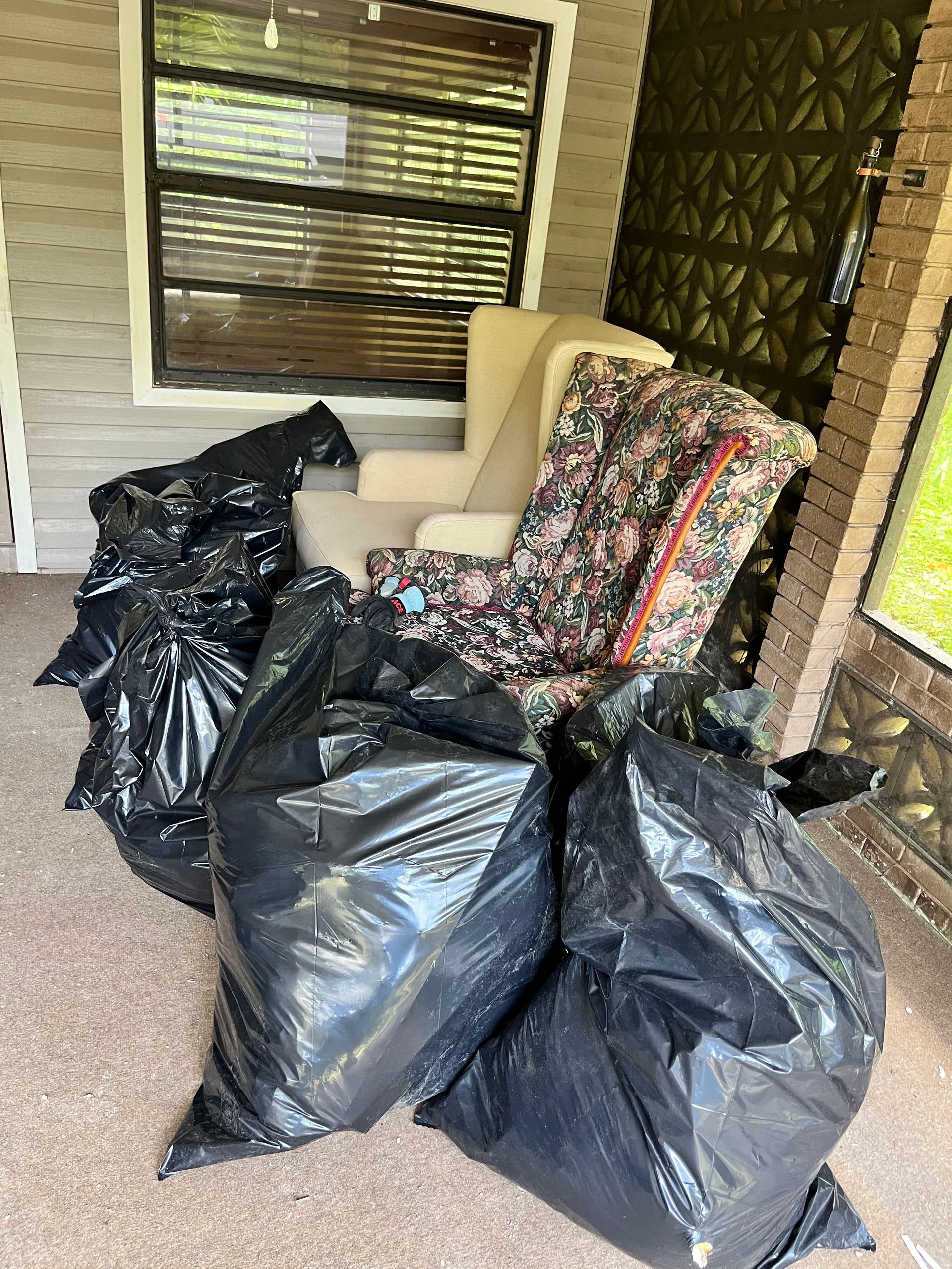 A living room filled with furniture and trash bags.