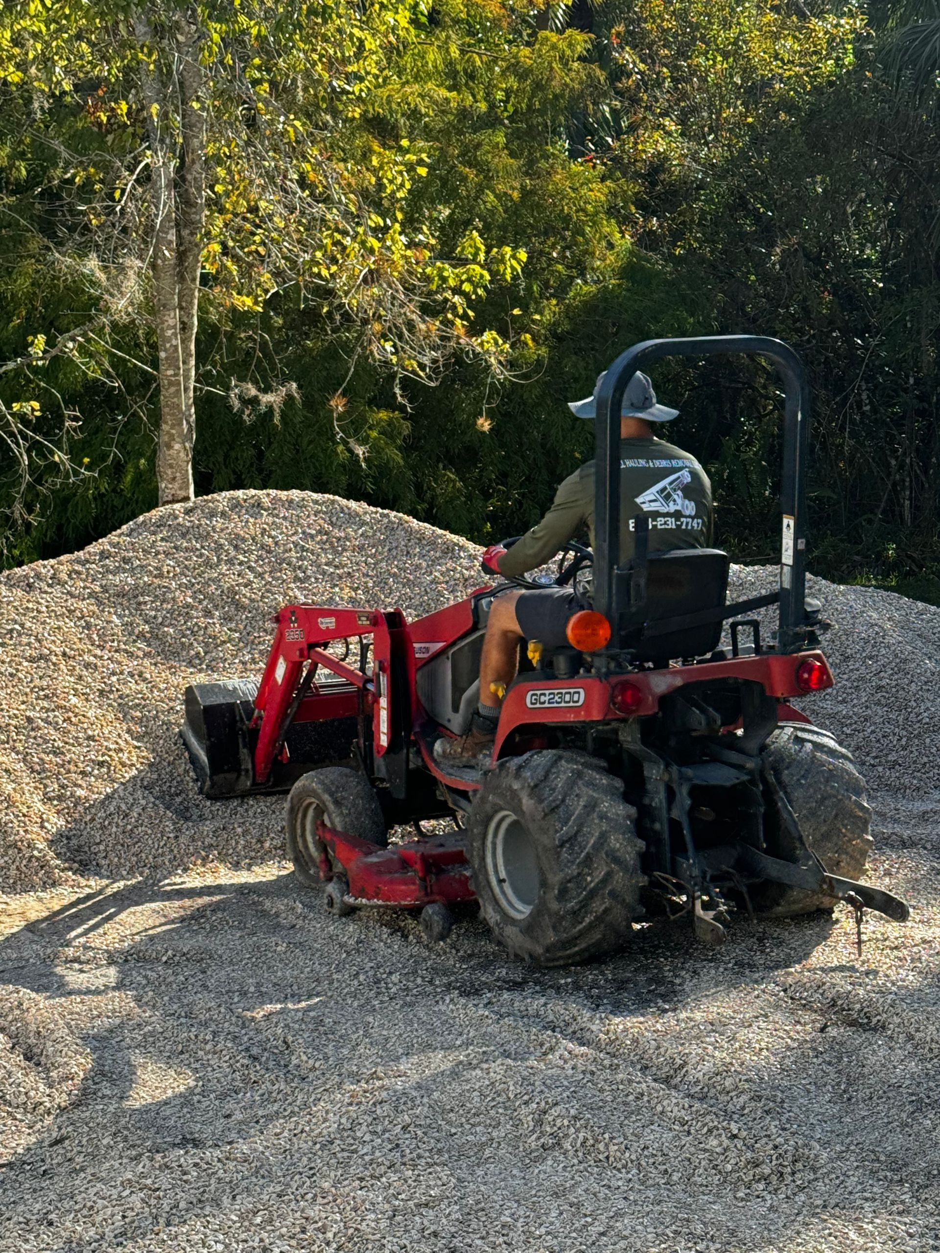 A man is riding a tractor on top of a pile of gravel.