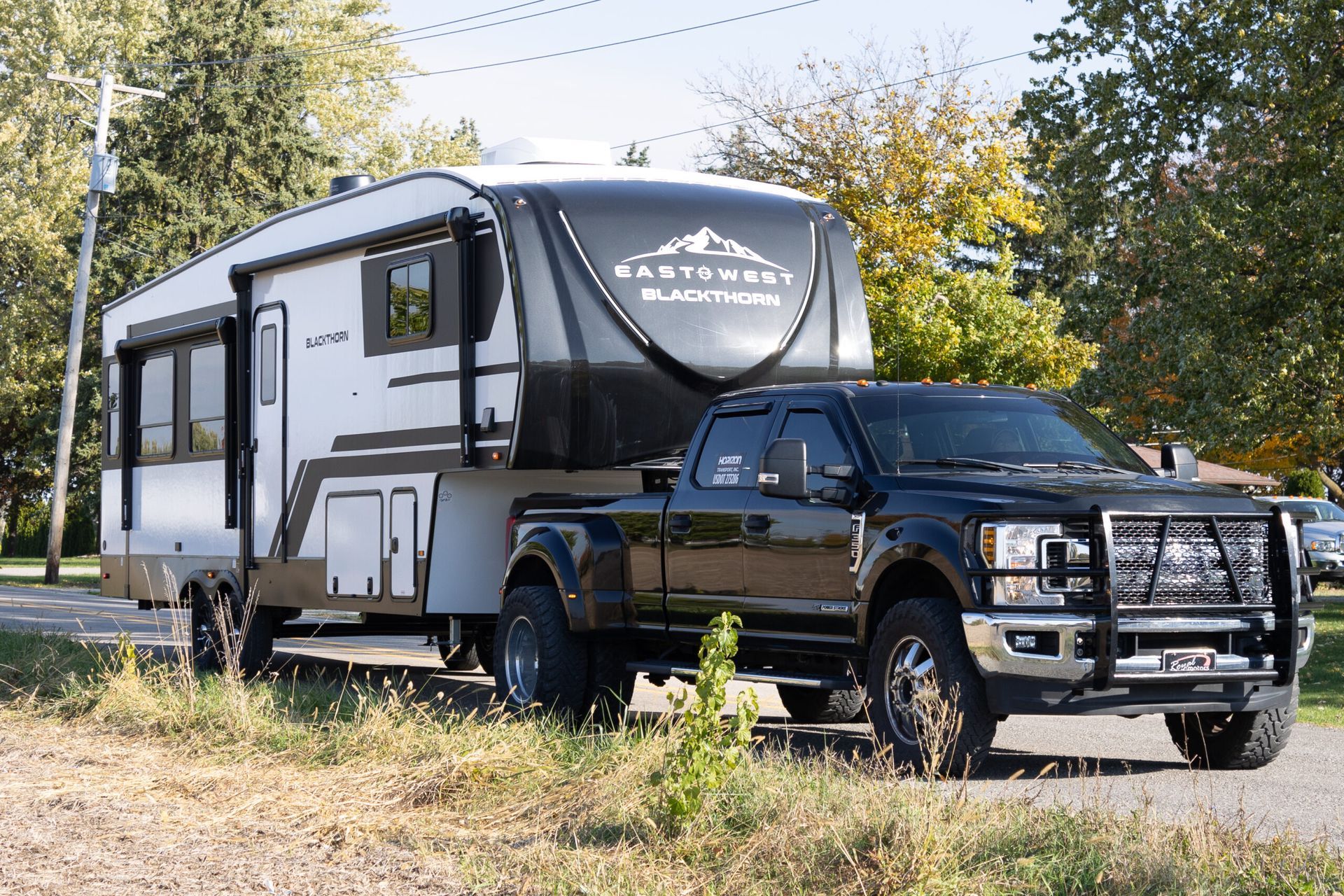 A truck is towing a trailer on a dirt road.