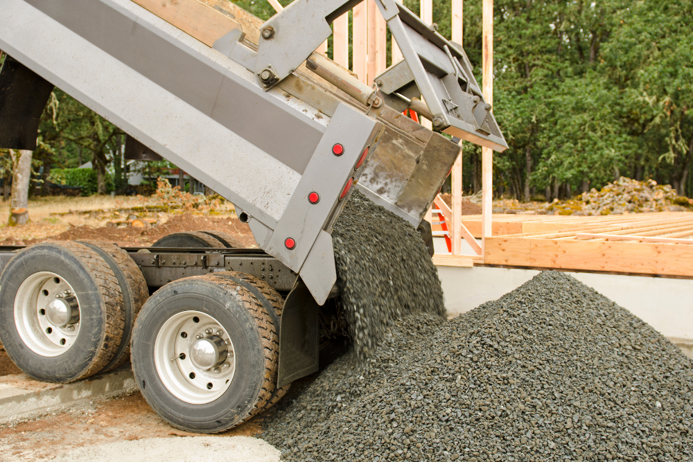A dump truck is being loaded with gravel at a construction site.