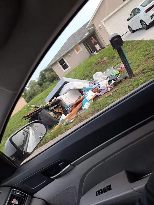 A car is parked in front of a pile of trash