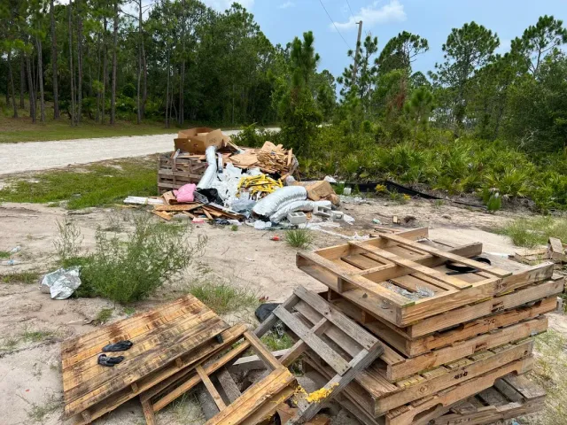 A pile of wooden pallets sitting on top of a dirt field.