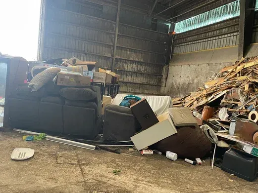 A pile of furniture is sitting on the ground in a warehouse.