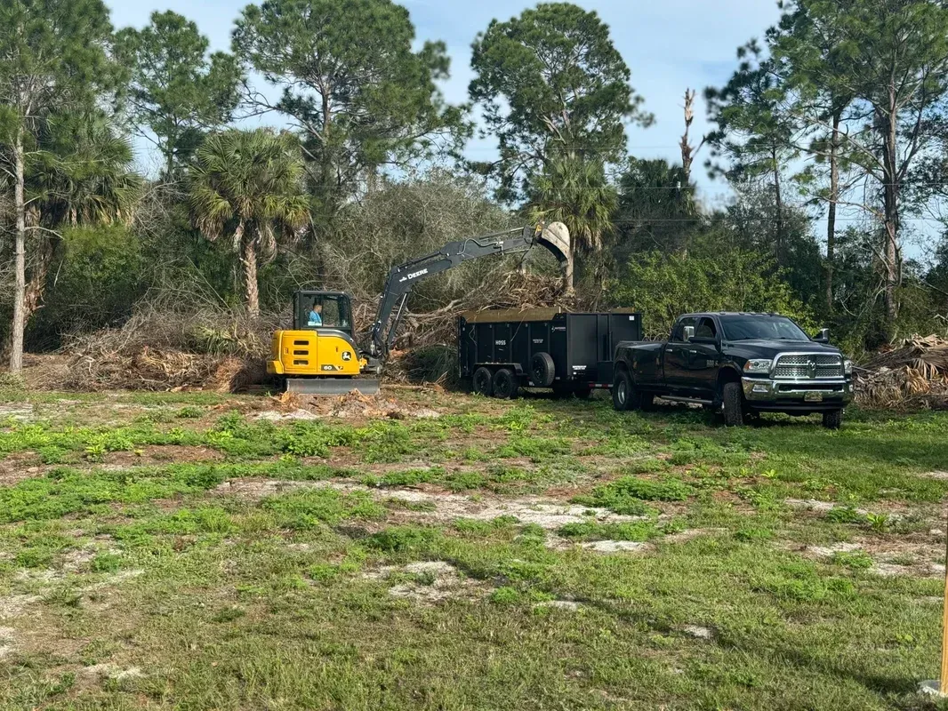 A truck and a bulldozer are parked in a grassy field.