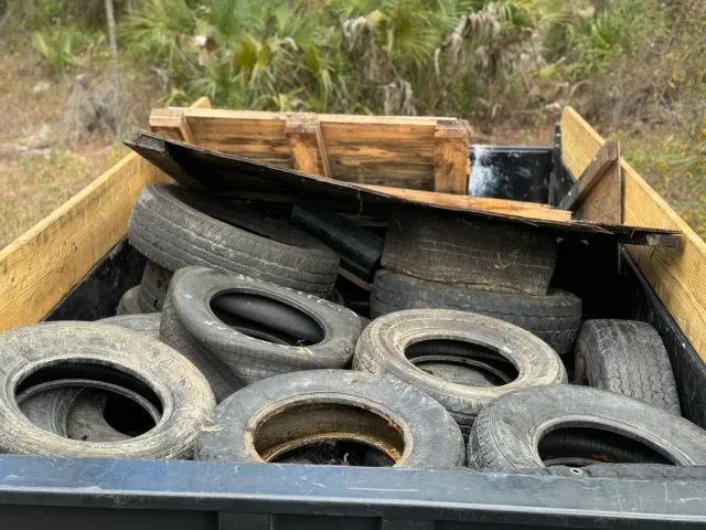 A dumpster filled with tires and a wooden pallet.