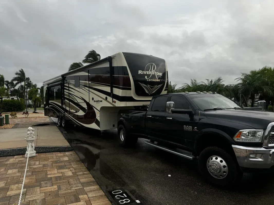 A truck is towing a trailer with a rv on it.