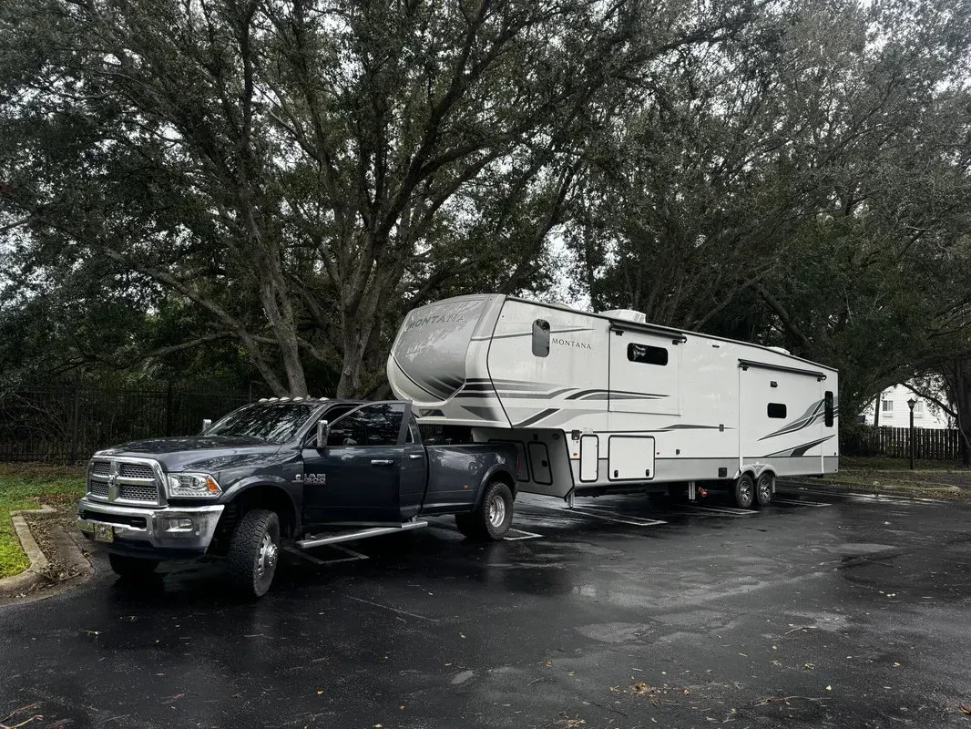 A truck is towing a trailer in a parking lot.