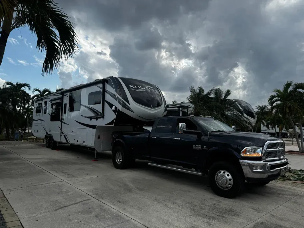 A rv is being towed by a truck in a parking lot.