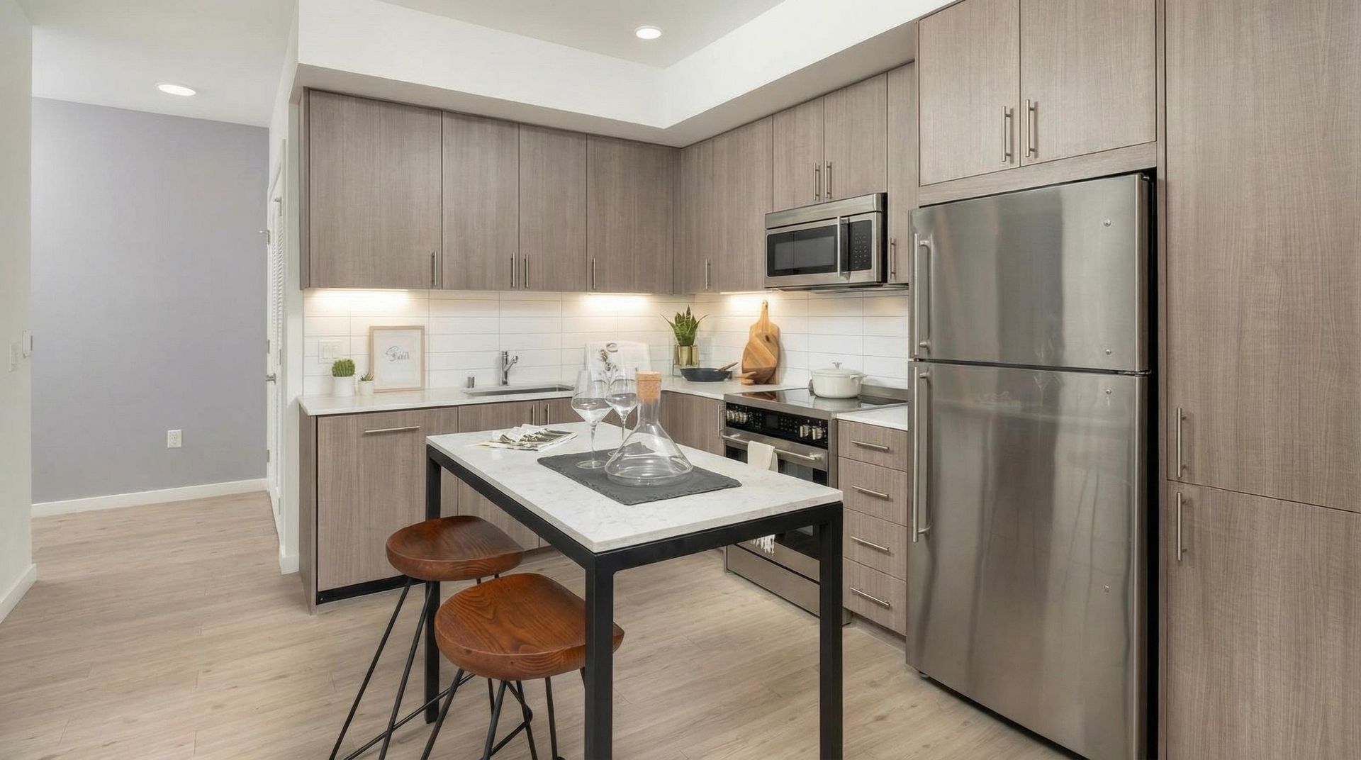 Bright modern apartment kitchen with wood cabinets, stainless steel appliances, and a small island.