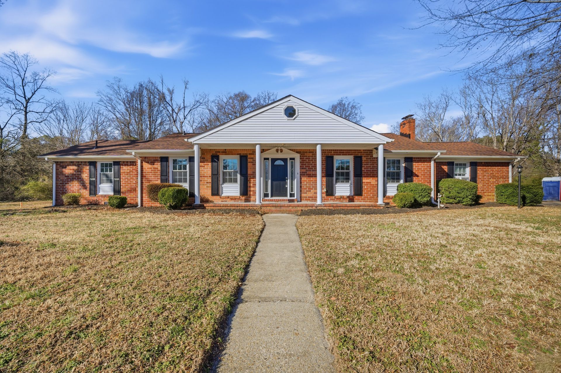 outside brick ranch with long sidewalk up to porch