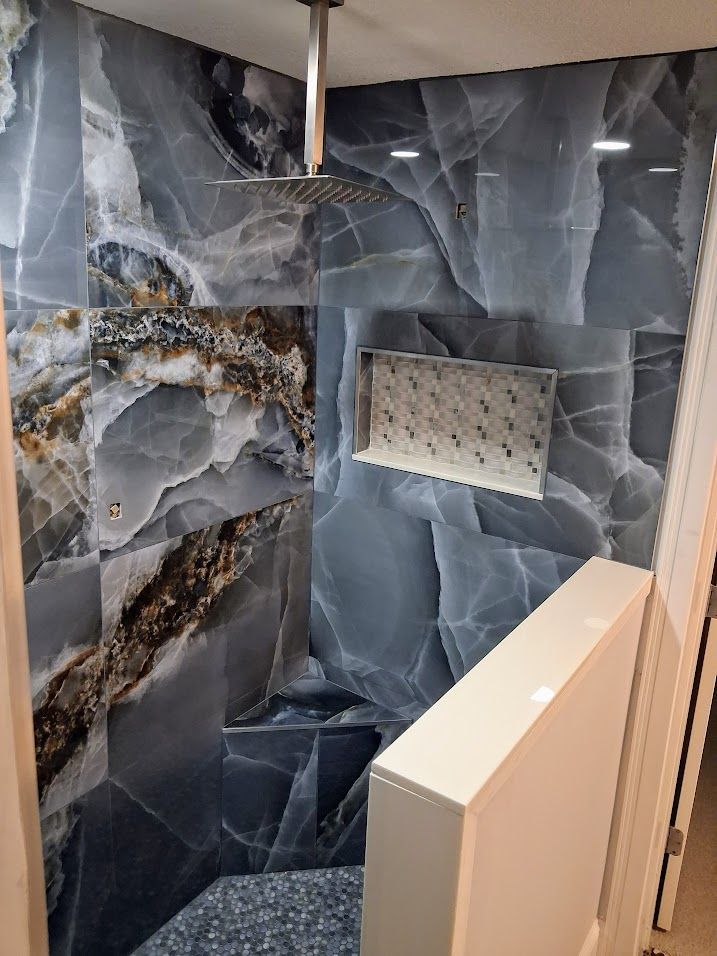 Dark blue marble shower with white tile accents and a built-in bench in a bathroom