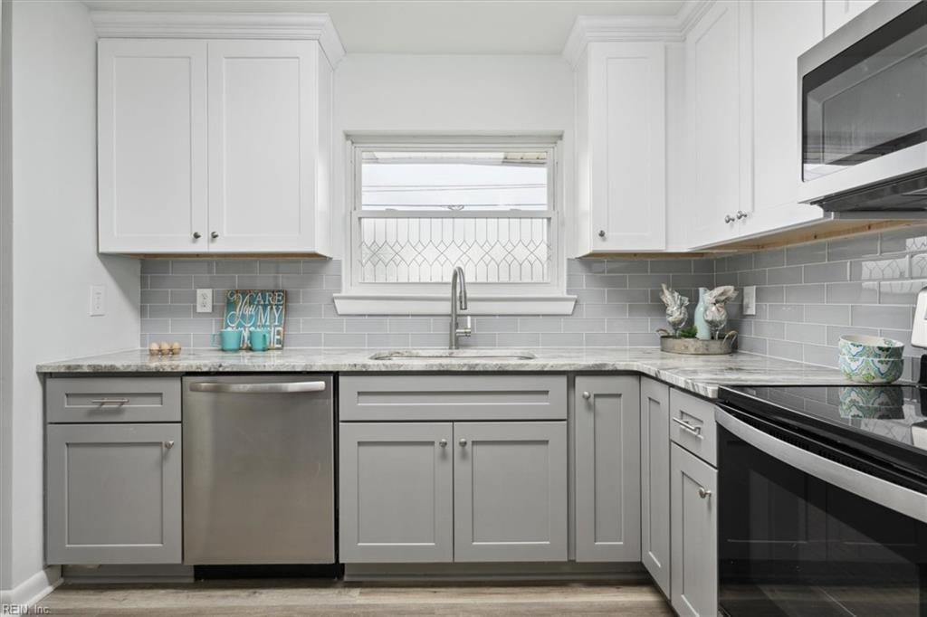 Bright white modern kitchen with stainless steel appliances and a window over the sink