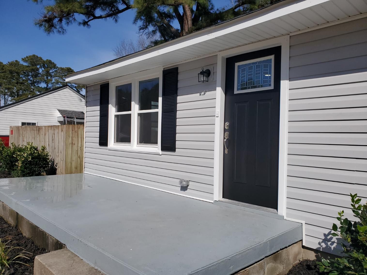 Gray house exterior with porch, black door and shutters, and white trim.