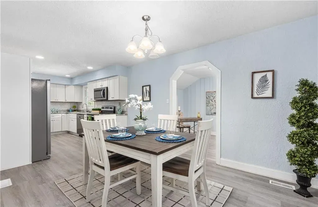 Bright dining room with white chairs, wood table, and blue walls in an open kitchen layout