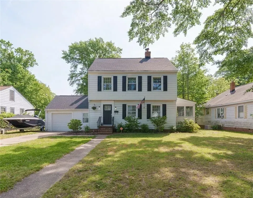 White two-story house with black shutters, a small porch, and a lawn.